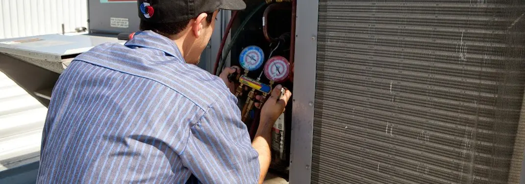HVAC technician servicing a condenser unit in Raymore