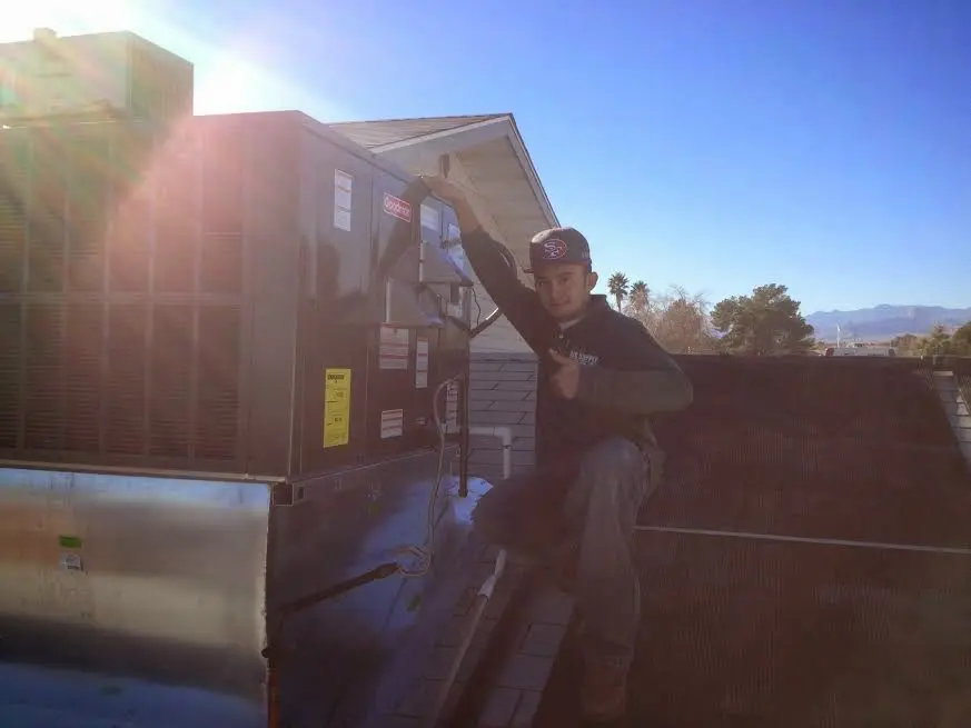 HVAC technician performing AC Tune-Up on a rooftop unit in Raymore